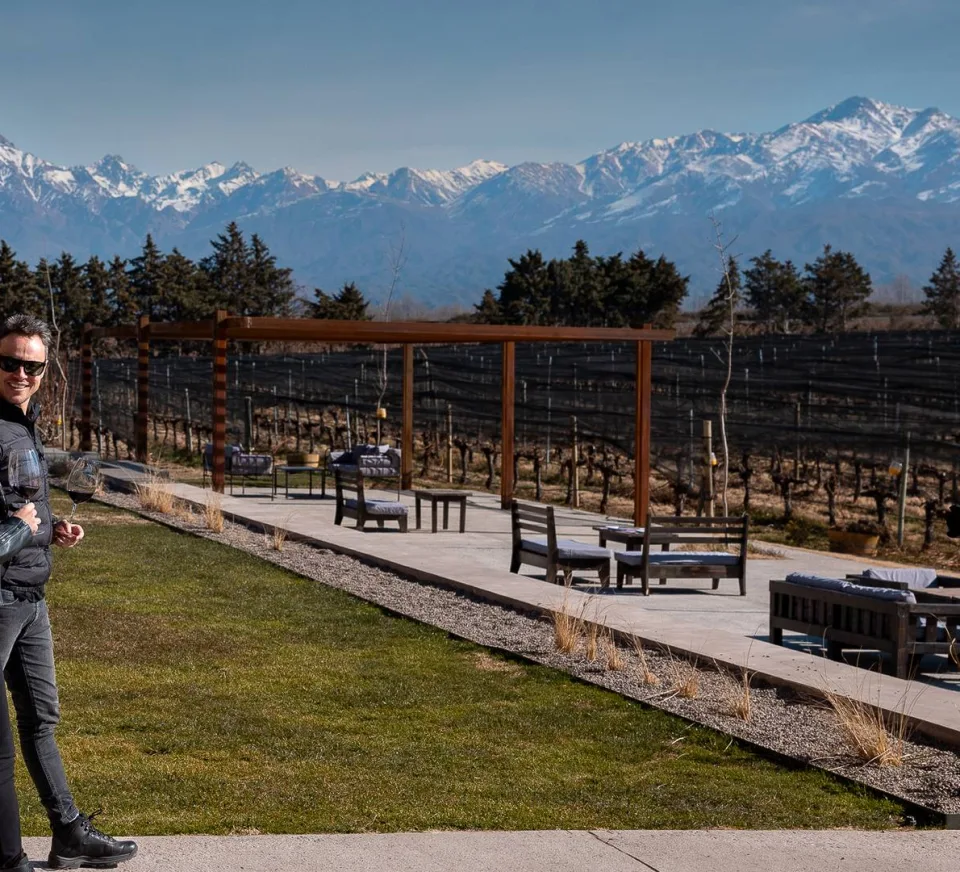 Halley com uma taça de vinho em uma área de estar entre as vinhas